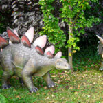 Zwei Dinosauriermodelle im Grünen im DinoWeltWäldchen Eckartsberga zwischen Bäumen und Sträuchern